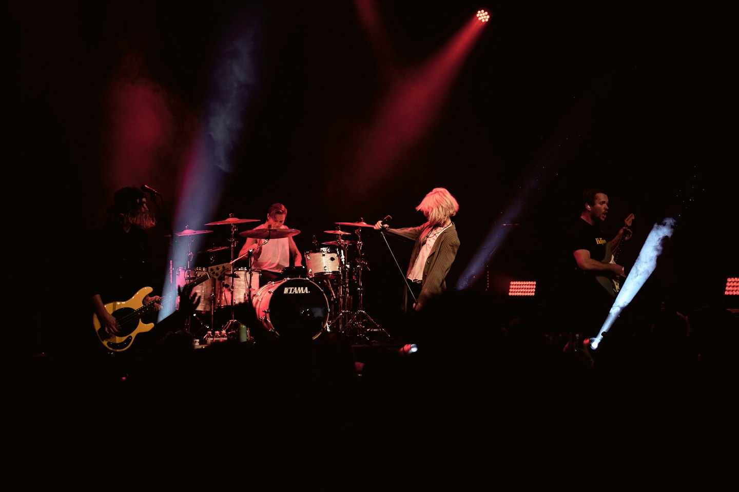 Musicisti suonano sul palco con strumenti.