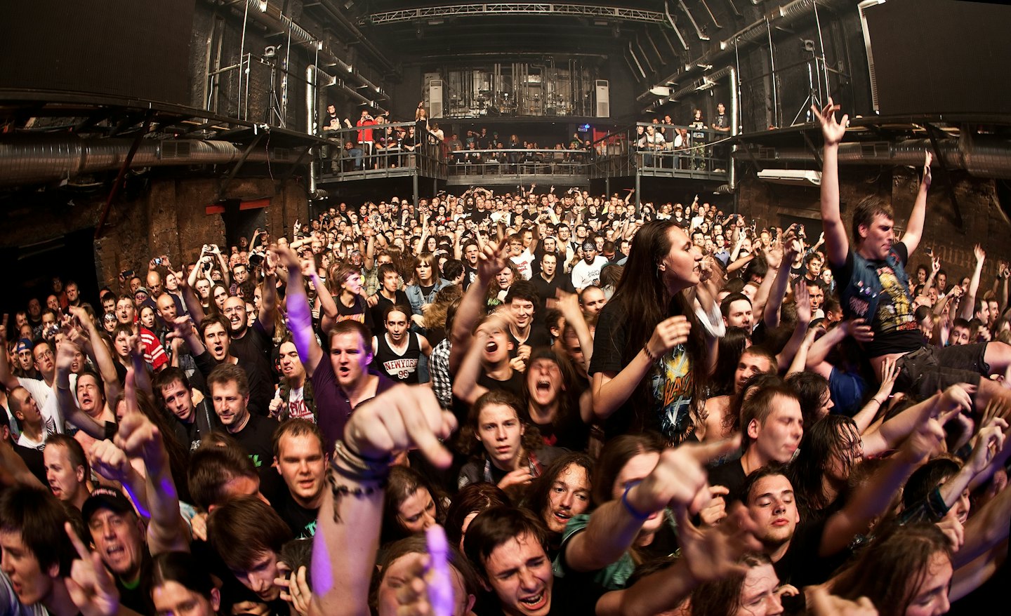 Folla che acclama e fa il crowd-surfing a un vivace concerto al chiuso.