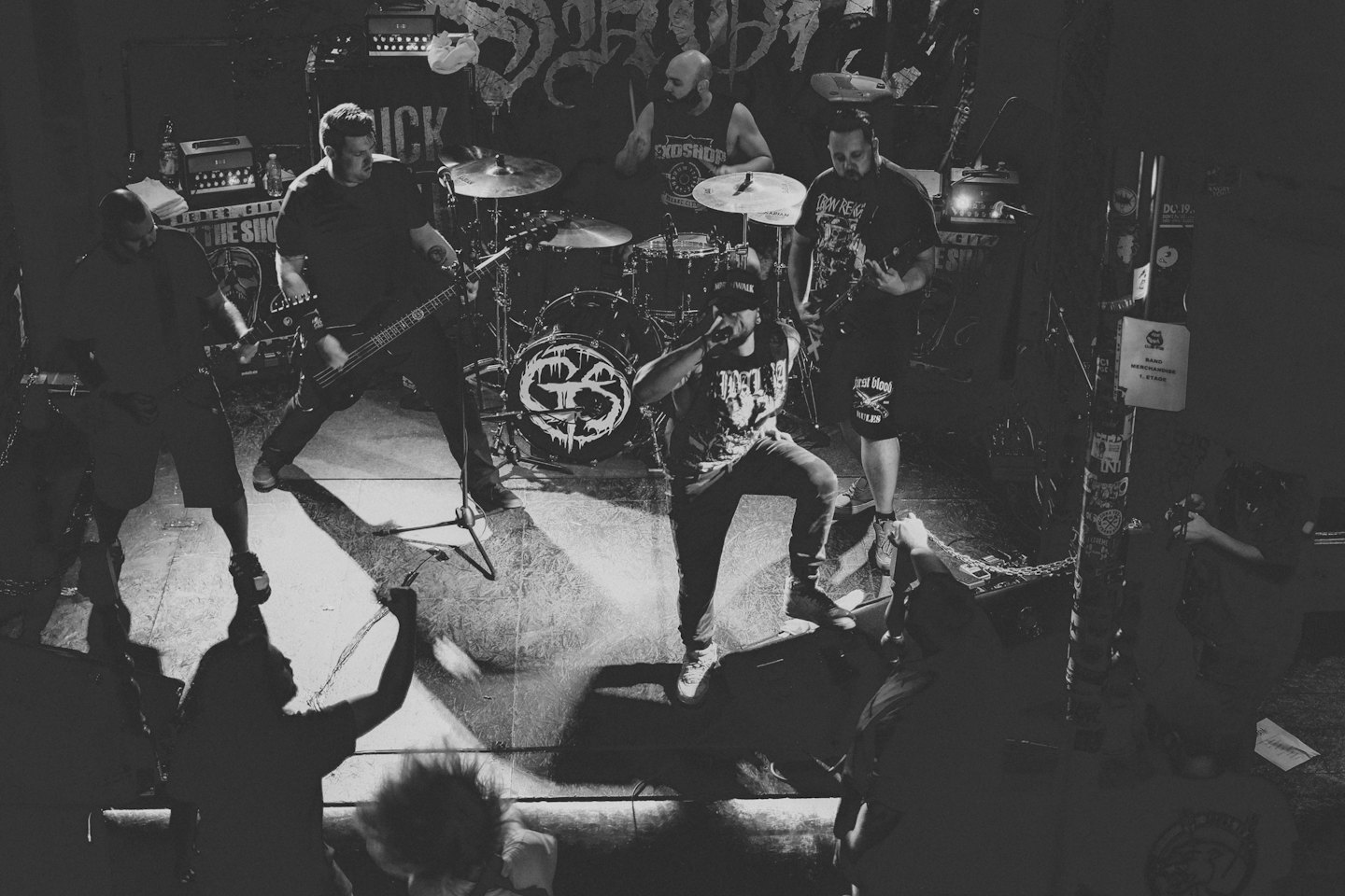 Una band heavy metal si esibisce dal vivo su un palco interno scarsamente illuminato.
